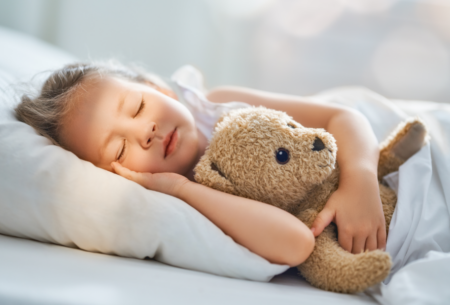 Girl sleeping with teddy bear.