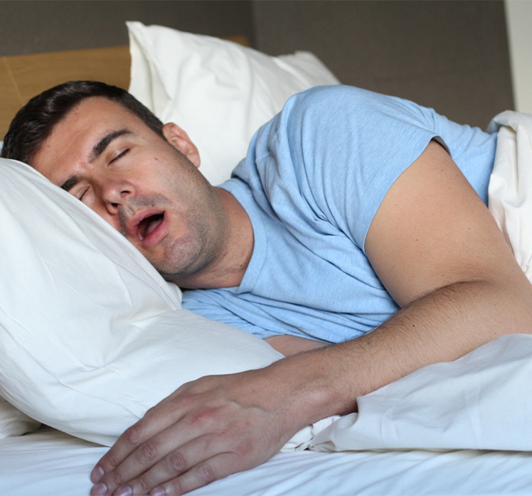 Man in light blue shirt snoring in bed.